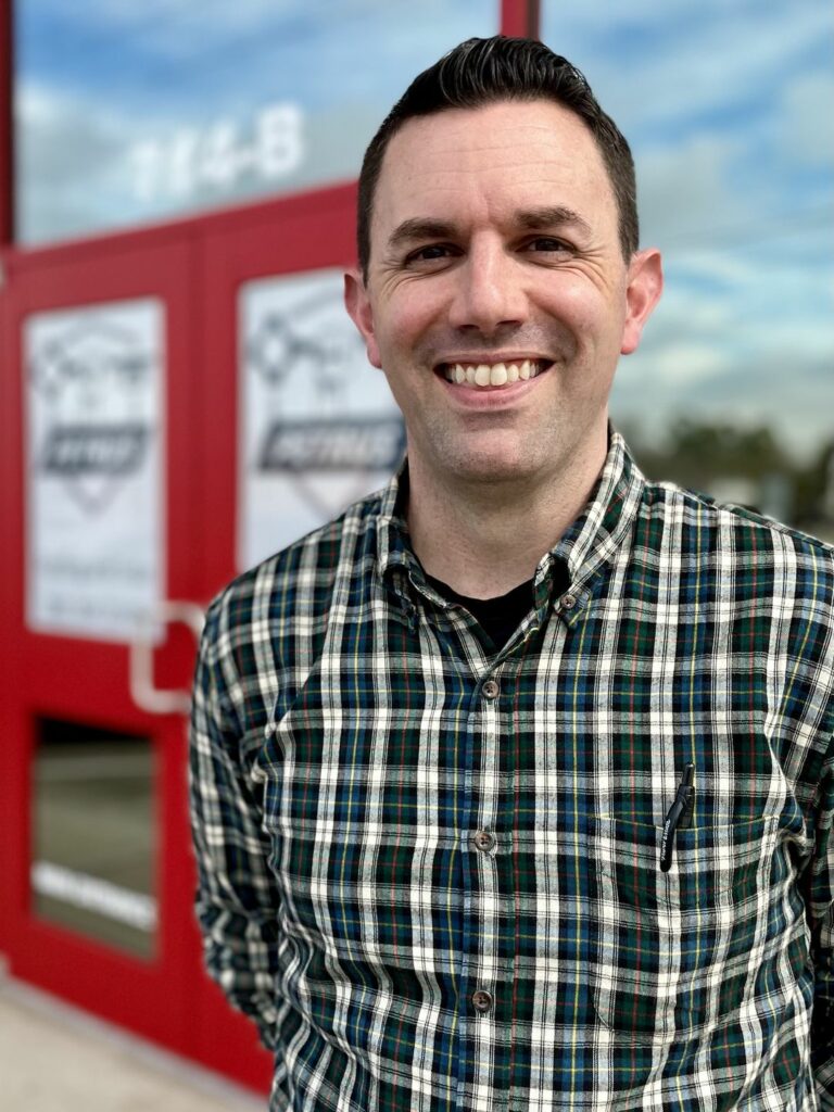 Brian smiling in front of Petrus Roofing main doors.