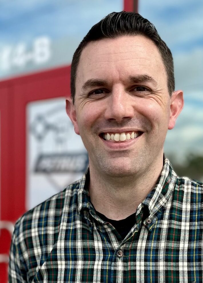 Brian smiling in front of Petrus Roofing main doors.