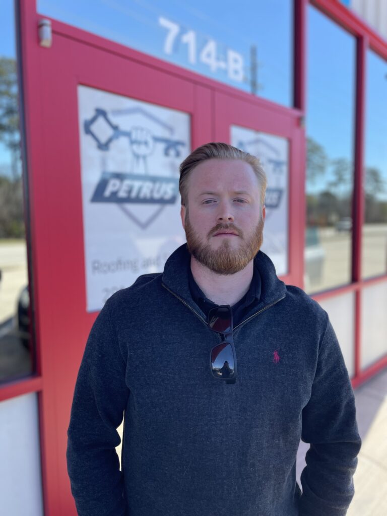 Caleb stands in front of the Petrus doors wearing a hoodie.